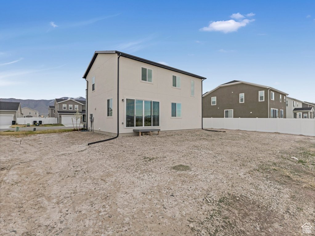 Rear view of property featuring stucco siding and fence