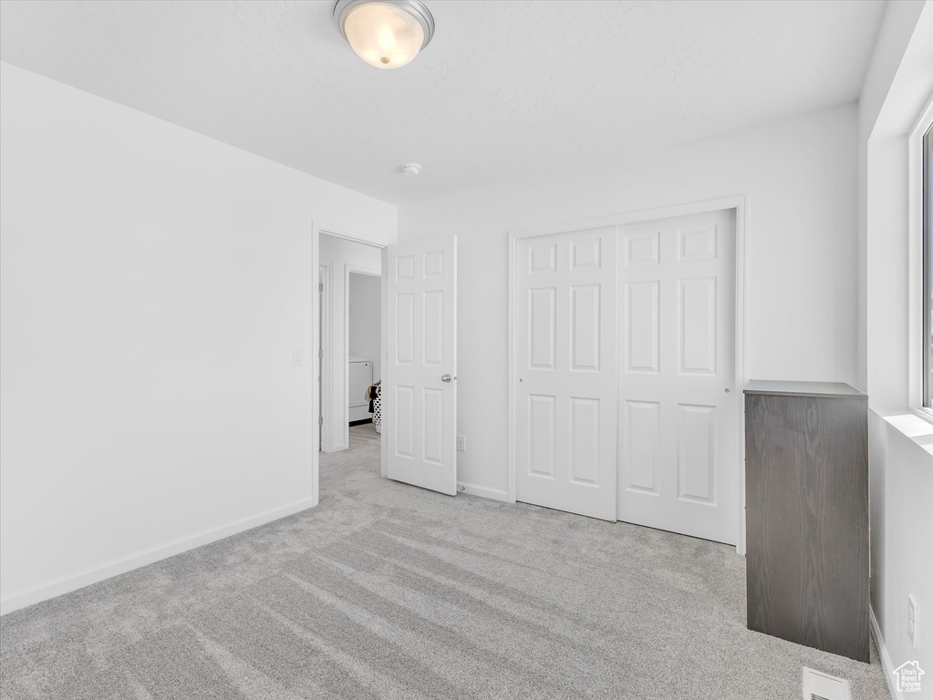 Unfurnished bedroom with visible vents, baseboards, a closet, and light colored carpet