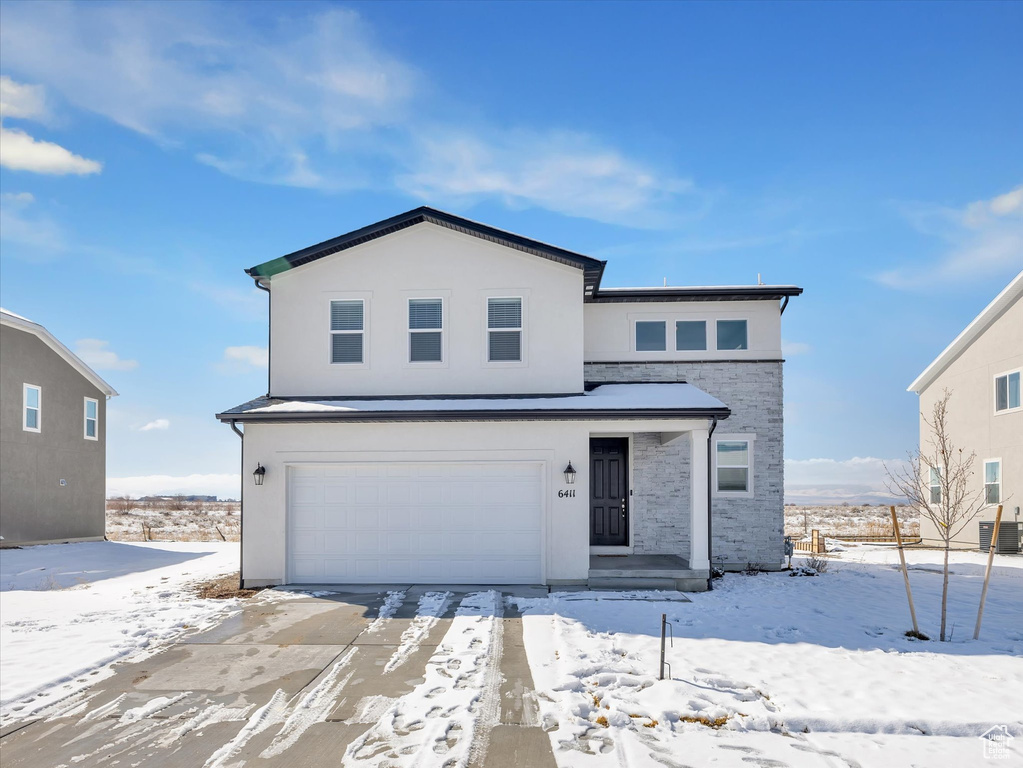 View of front of property with a garage, stone siding, and stucco siding