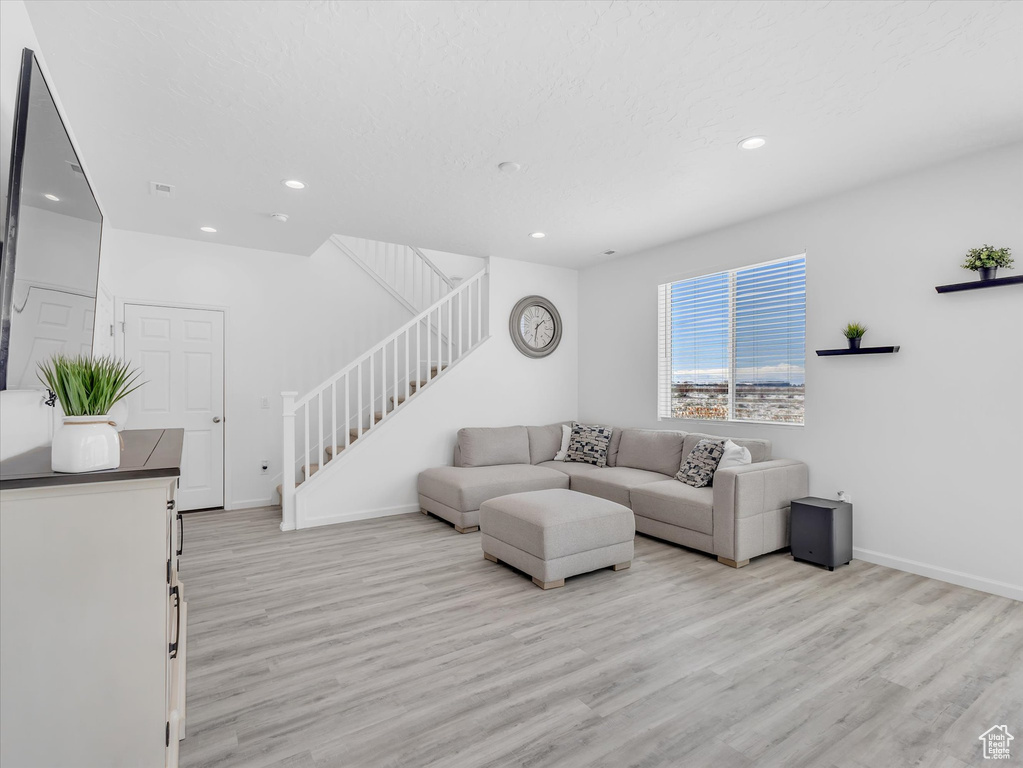 Living area with baseboards, stairway, light wood-type flooring, and recessed lighting