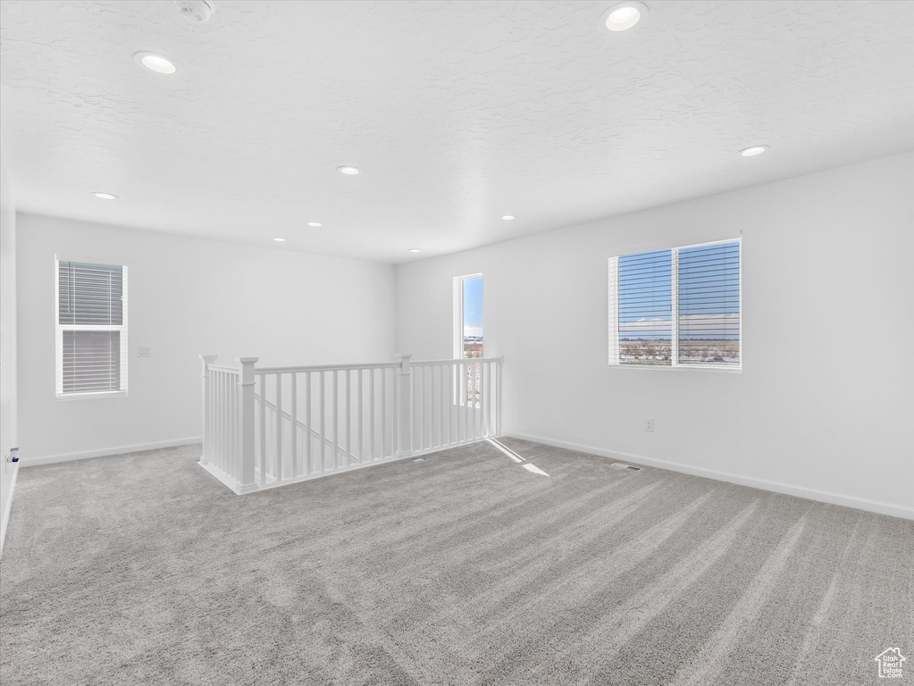 Carpeted empty room featuring a textured ceiling and recessed lighting