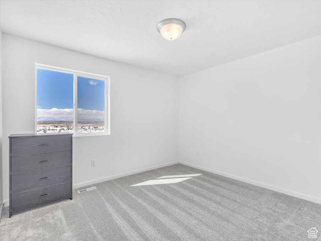 Spare room featuring light carpet, visible vents, and baseboards