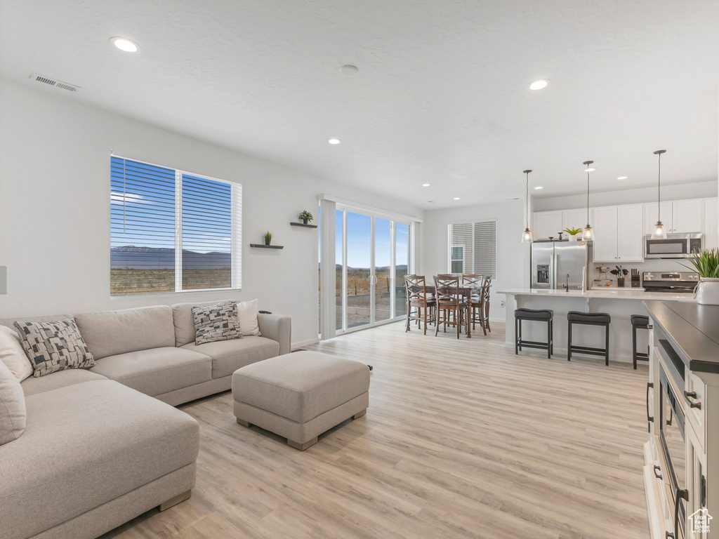 Living room featuring recessed lighting, light wood-style floors, baseboards, and visible vents
