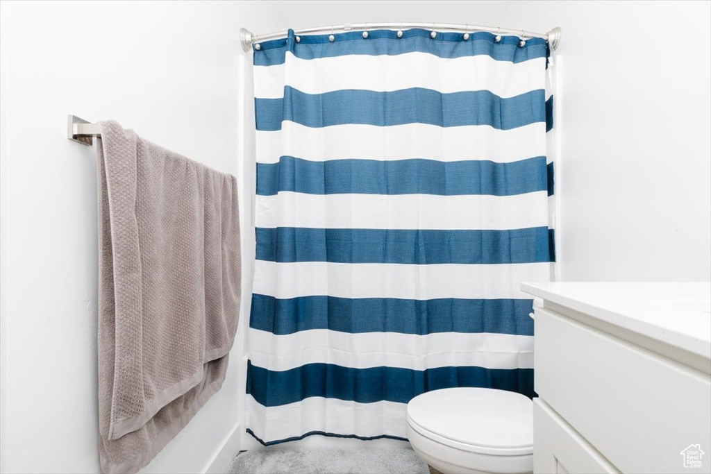 Bathroom with toilet, vanity, and curtained shower