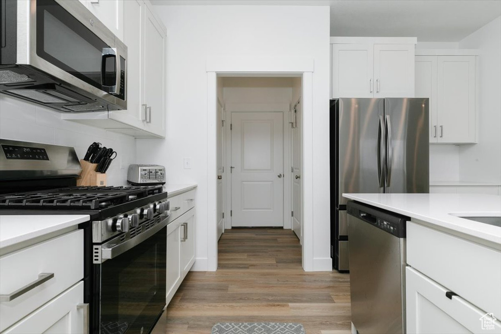 Kitchen featuring white cabinetry, stainless steel appliances, and light hardwood / wood-style flooring