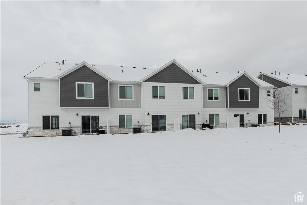 Snow covered rear of property featuring central AC