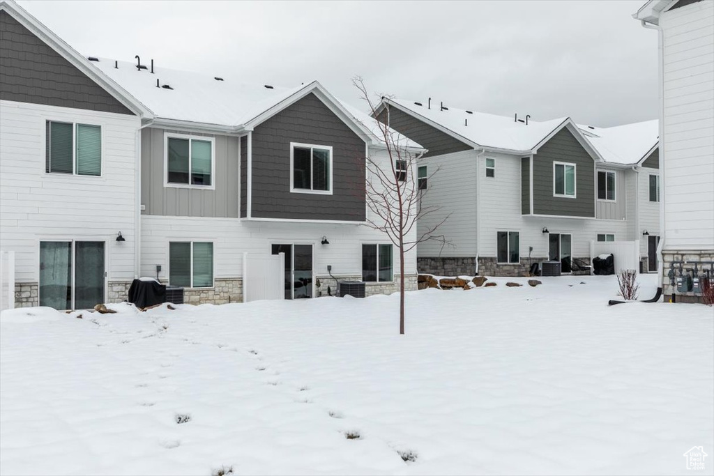 Snow covered rear of property with central air condition unit