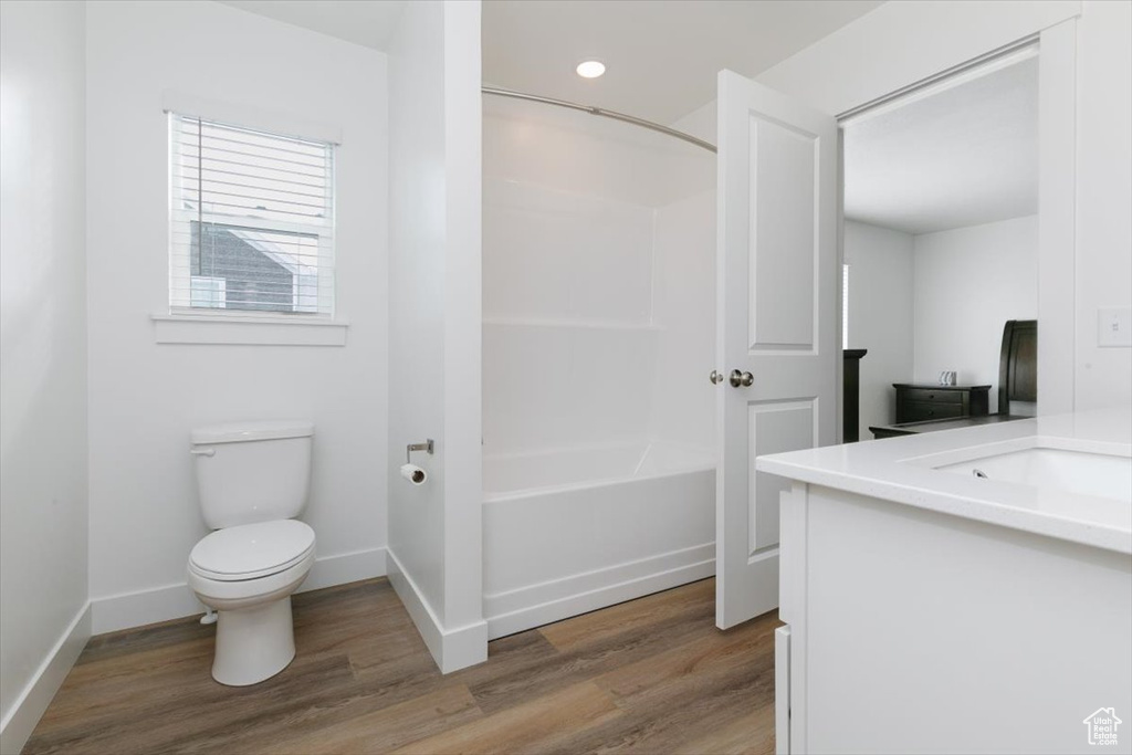 Full bathroom featuring toilet, vanity, shower / tub combination, and wood-type flooring