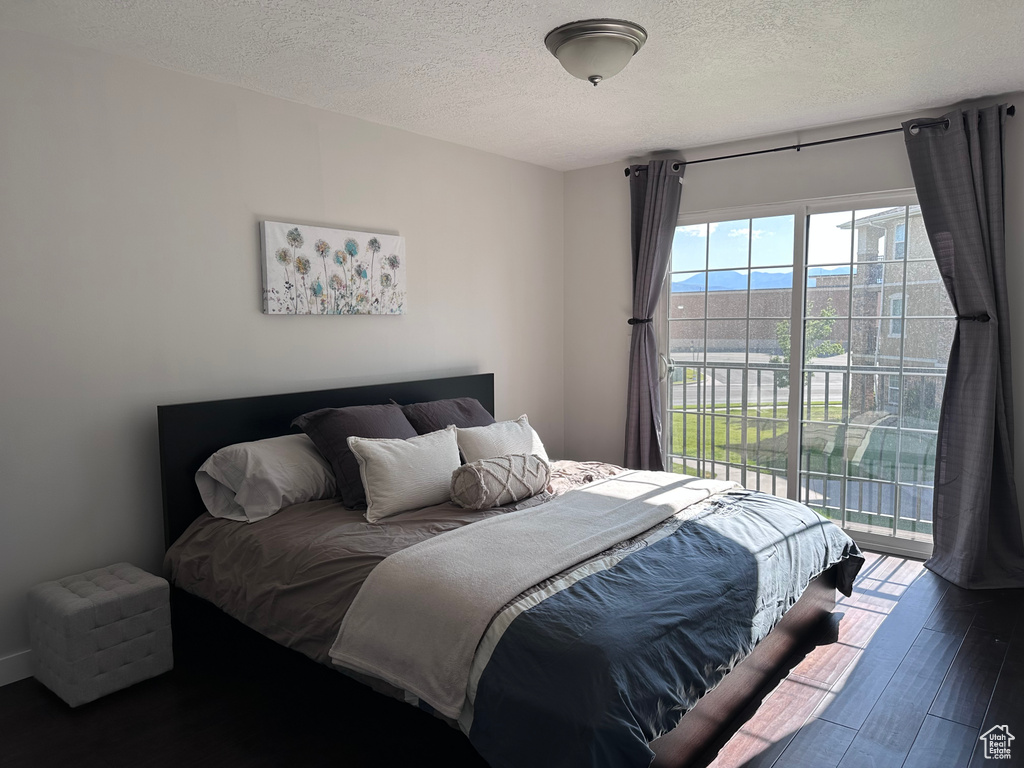 Bedroom featuring access to outside, a textured ceiling, and wood finished floors