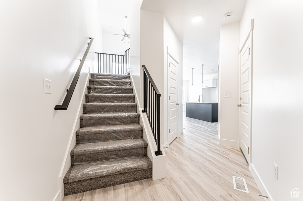 Stairs with ceiling fan, wood finished floors, and baseboards