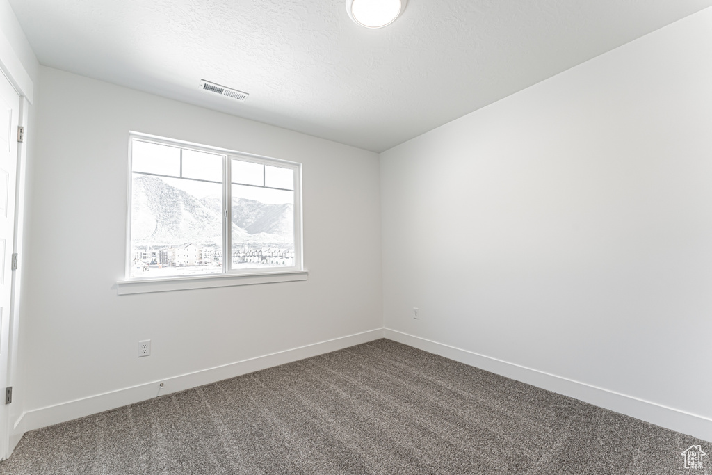 Empty room with dark carpet and baseboards