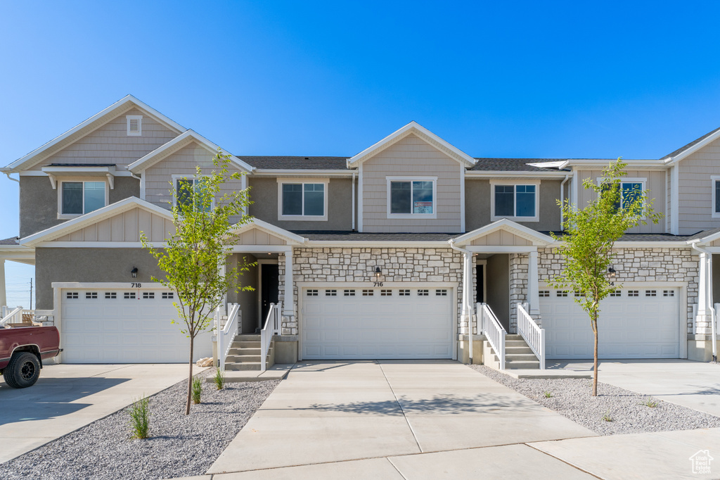 View of front of home with board and batten siding, driveway, a garage, and stone siding