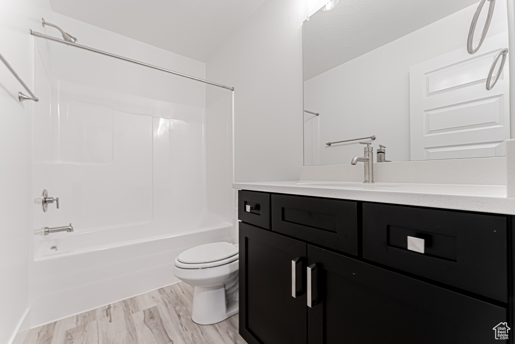 Full bath featuring vanity, toilet, bathtub / shower combination, and wood finished floors