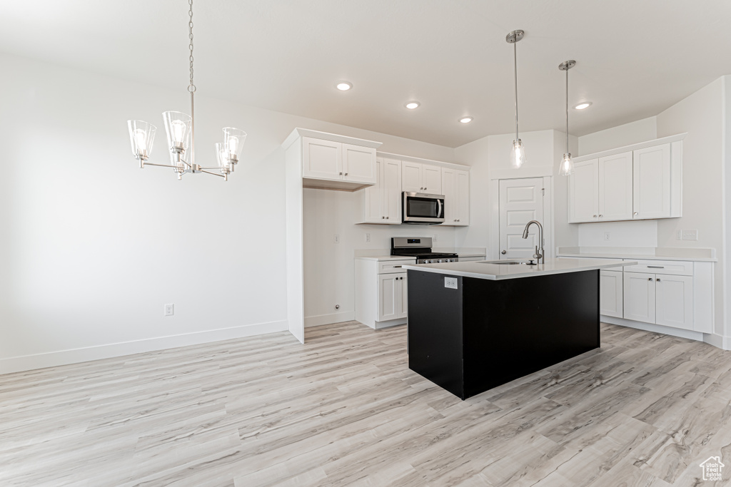 Kitchen featuring a sink, stainless steel appliances, light countertops, baseboards, and a chandelier
