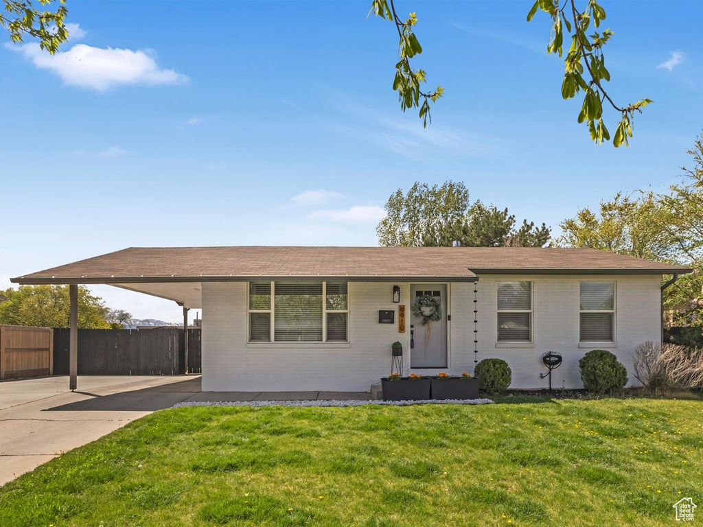 Ranch-style home with fence, a front lawn, a carport, and brick siding
