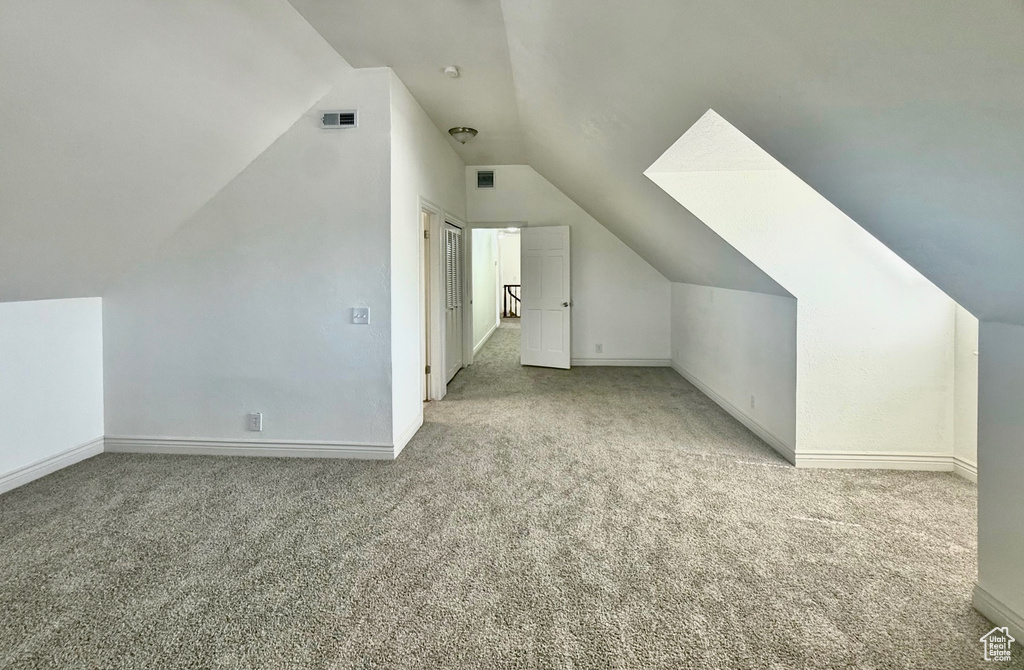 Additional living space with carpet flooring and vaulted ceiling