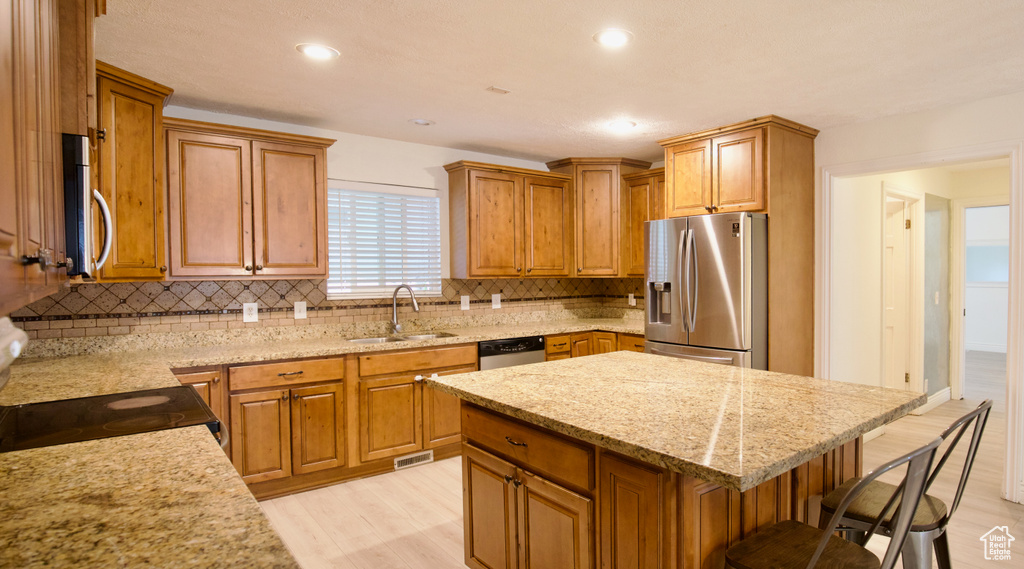 Kitchen featuring stainless steel appliances, a sink, tasteful backsplash, light stone countertops, and recessed lighting