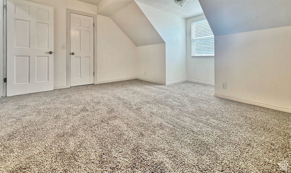 Additional living space featuring vaulted ceiling and carpet floors