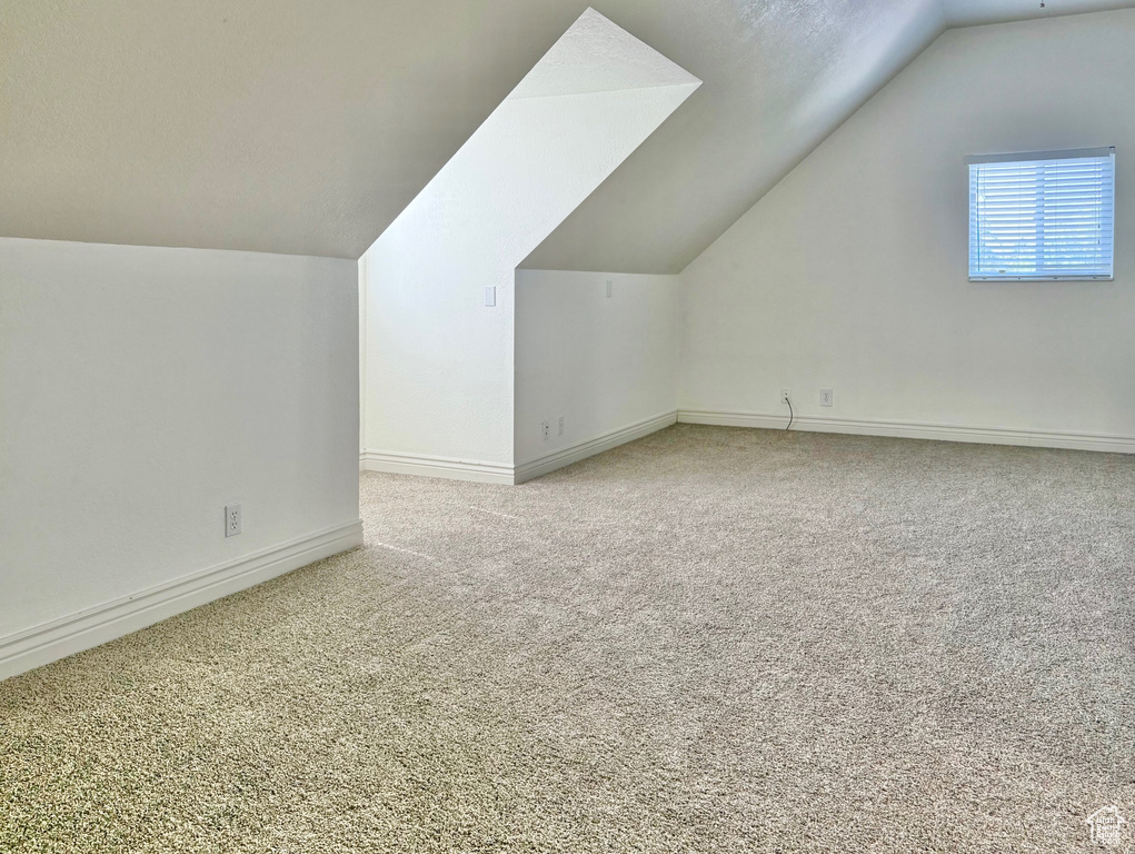Additional living space with lofted ceiling and carpet flooring