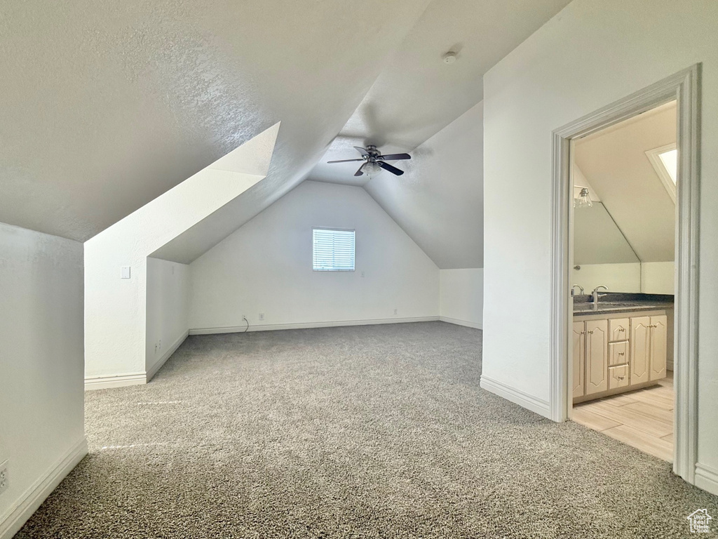Additional living space featuring light colored carpet, ceiling fan, and lofted ceiling