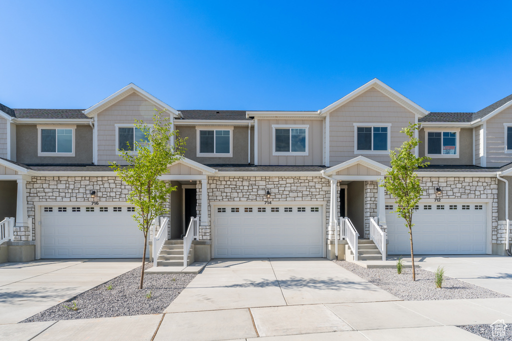View of front facade featuring a garage, concrete driveway, and stone siding
