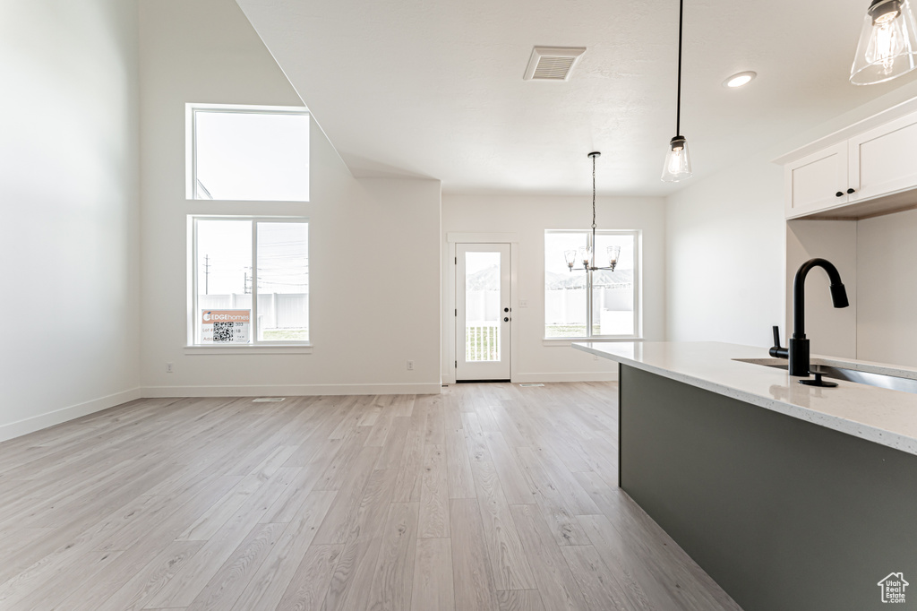Kitchen with light wood-type flooring, a chandelier, a sink, and decorative light fixtures
