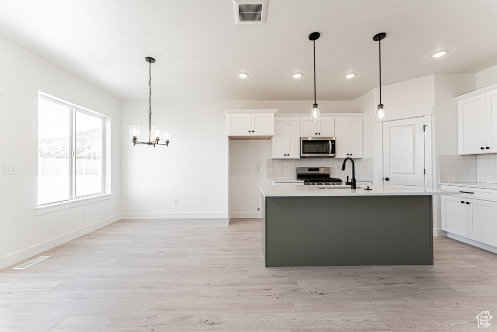 Kitchen with stainless steel appliances, light countertops, a sink, backsplash, and recessed lighting