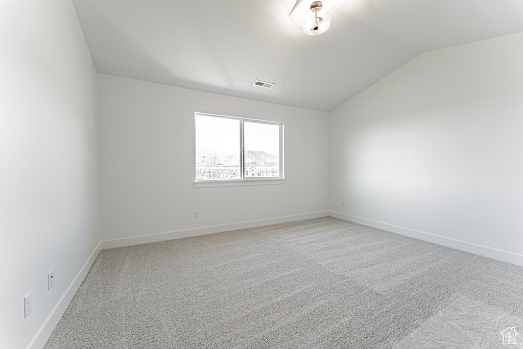 Spare room with vaulted ceiling, carpet, and baseboards