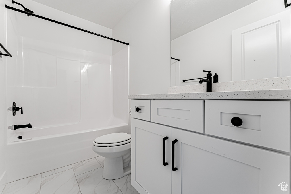 Bathroom with marble finish flooring, toilet, vanity, and  shower combination