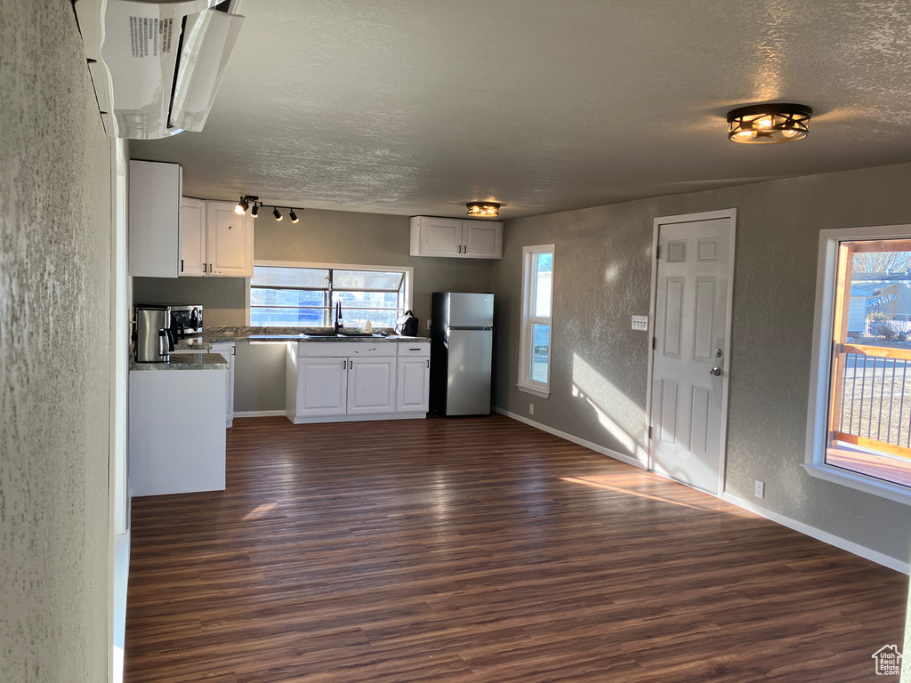 Kitchen featuring white cabinets, dark wood-style floors, freestanding refrigerator, a textured ceiling, and a sink