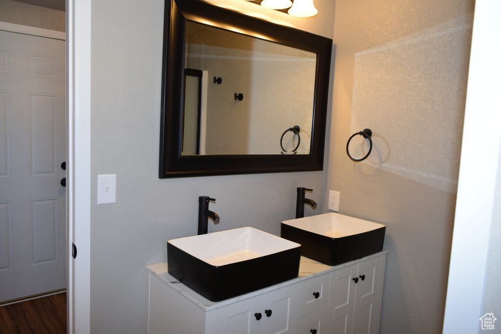 Bathroom with double vanity, a sink, and wood finished floors