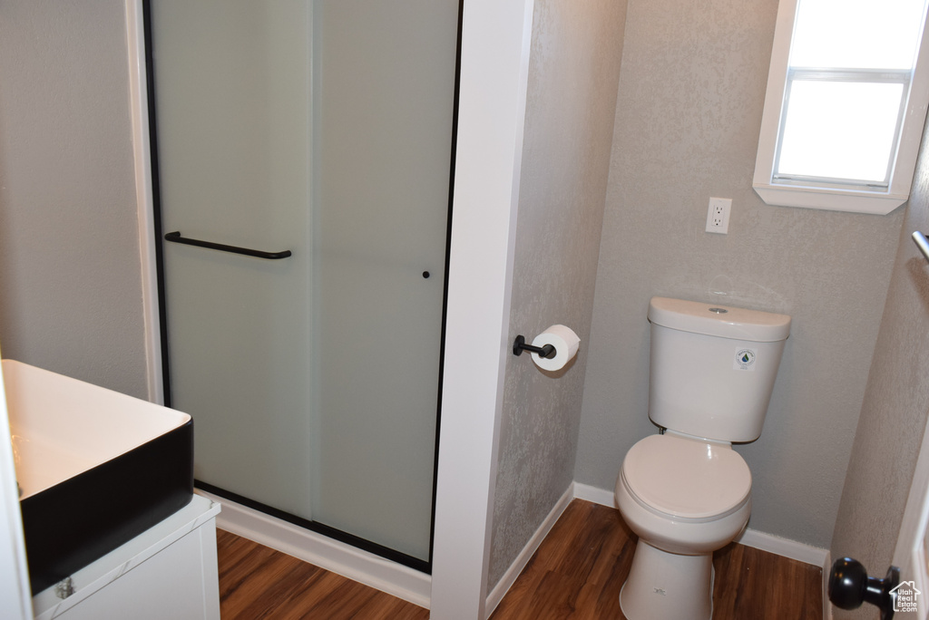 Full bath featuring baseboards, vanity, a shower stall, and wood finished floors