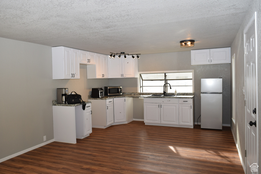 Kitchen featuring a textured ceiling, appliances with stainless steel finishes, dark wood-style flooring, and a sink