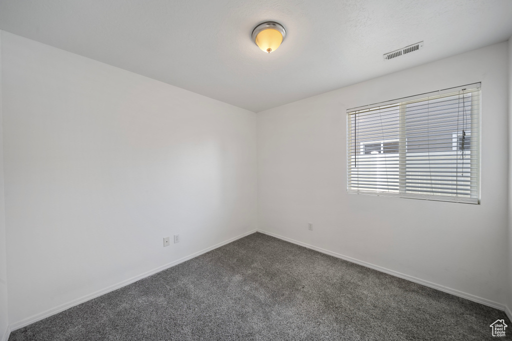 Spare room featuring visible vents, baseboards, and dark colored carpet