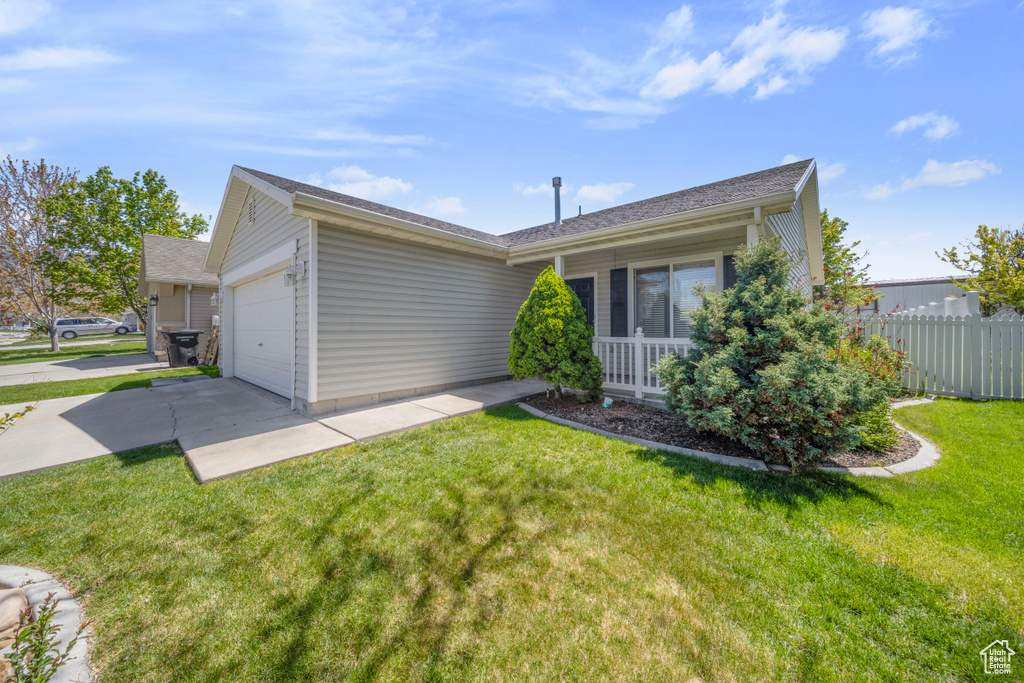 Ranch-style home featuring concrete driveway, an attached garage, fence, and a front lawn