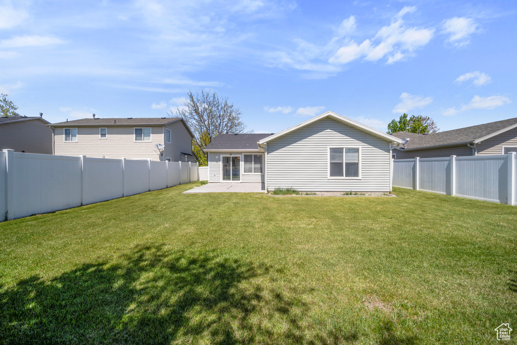 Rear view of property with a yard, a patio, and a fenced backyard