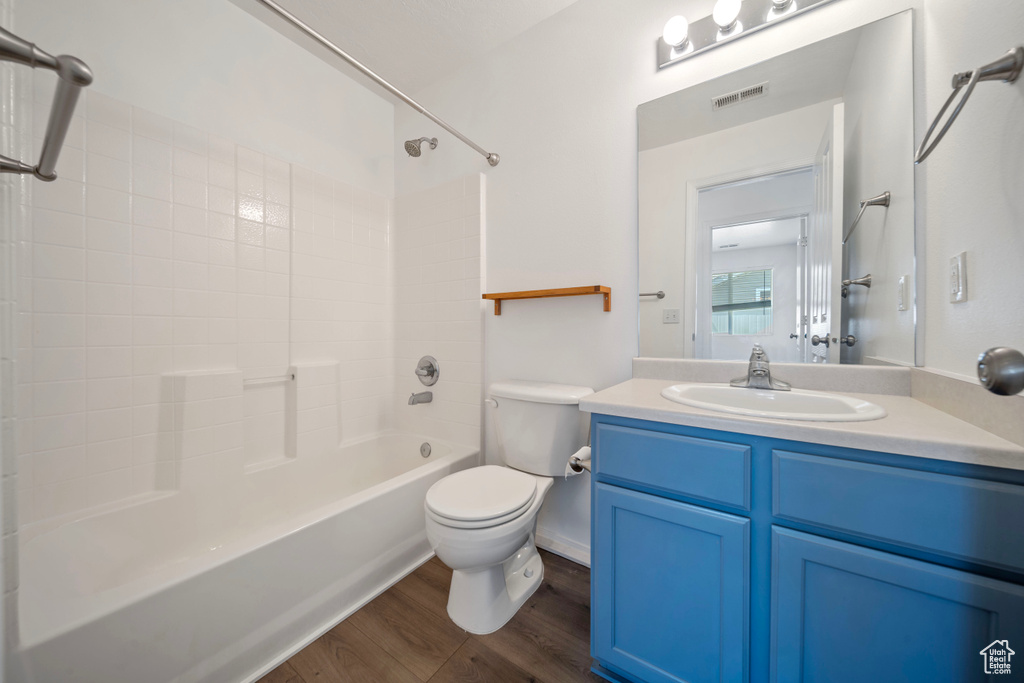 Bathroom featuring visible vents, vanity, wood finished floors, toilet, and  shower combination