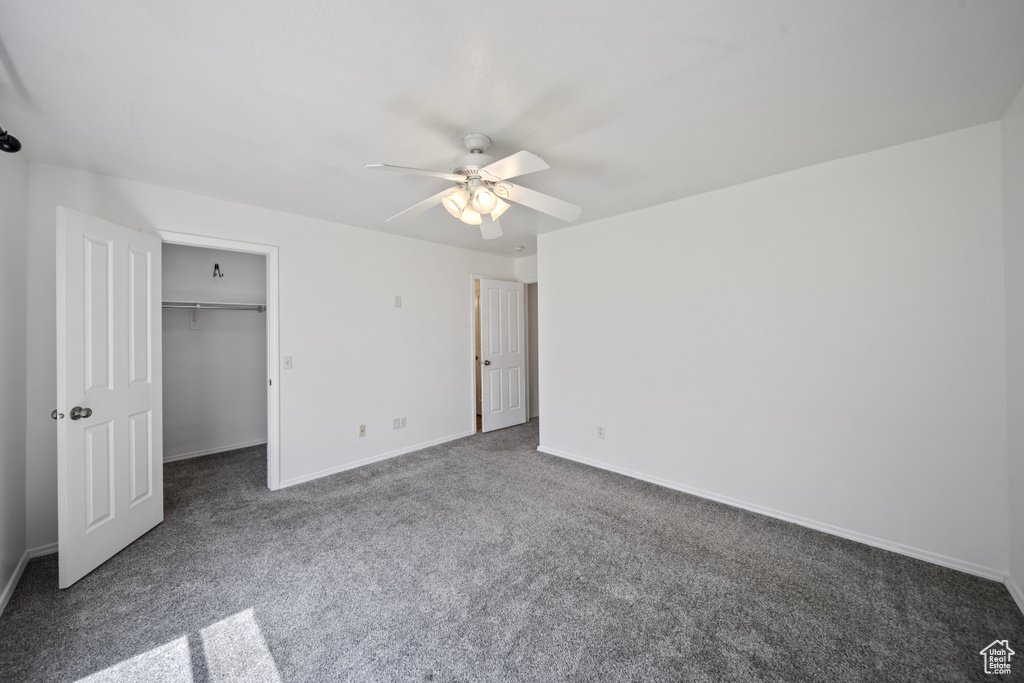 Unfurnished bedroom with ceiling fan, a walk in closet, carpet, baseboards, and a closet