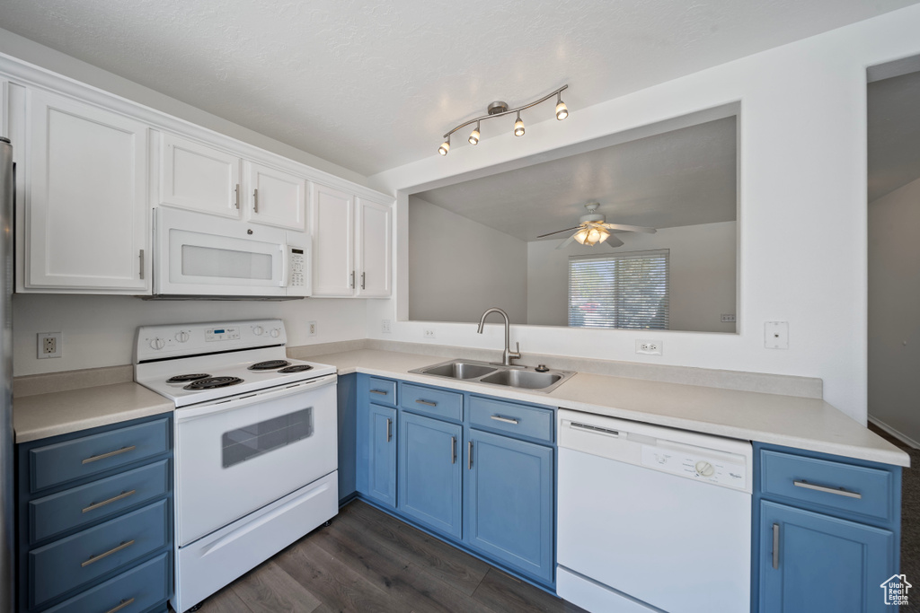 Kitchen featuring ceiling fan, blue cabinets, dark wood finished floors, a sink, and white appliances