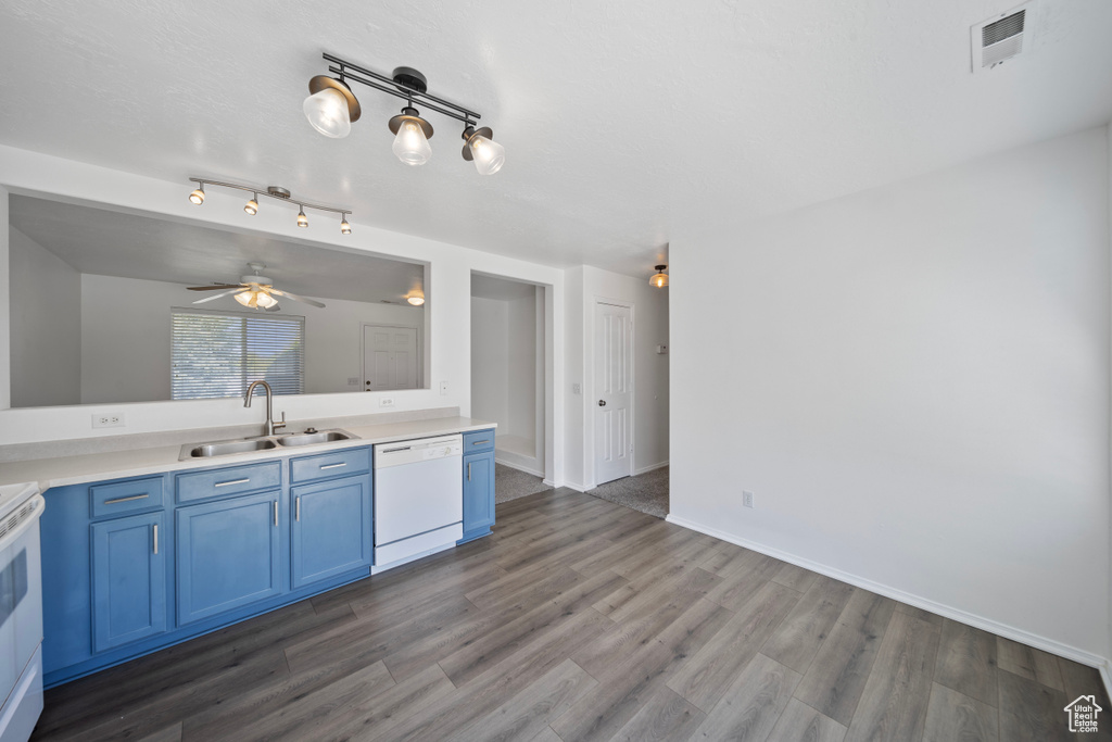 Kitchen with wood finished floors, a sink, blue cabinets, and white appliances