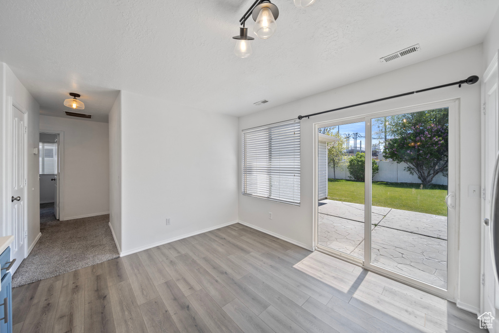 Interior space with baseboards, a textured ceiling, visible vents, and wood finished floors