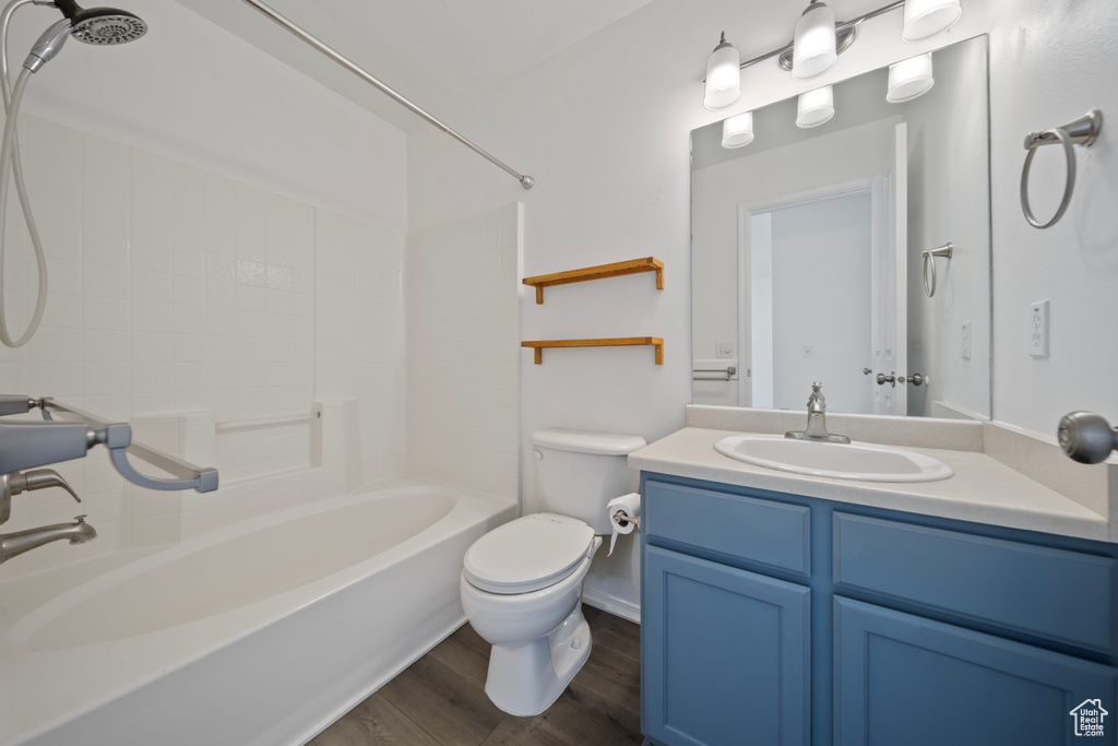 Full bath with vanity, toilet, wood finished floors, and  shower combination