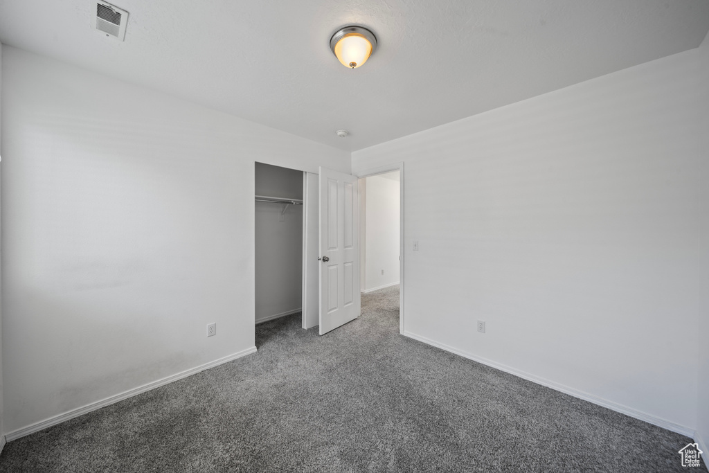 Unfurnished bedroom with carpet flooring, baseboards, visible vents, and a closet