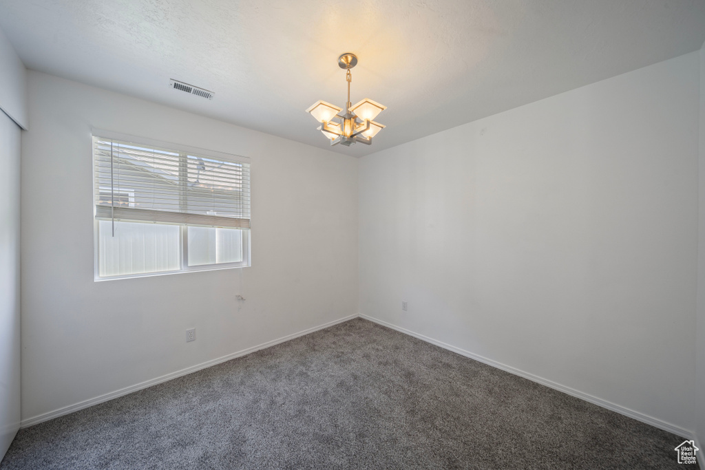 Unfurnished room with visible vents, carpet, baseboards, and an inviting chandelier