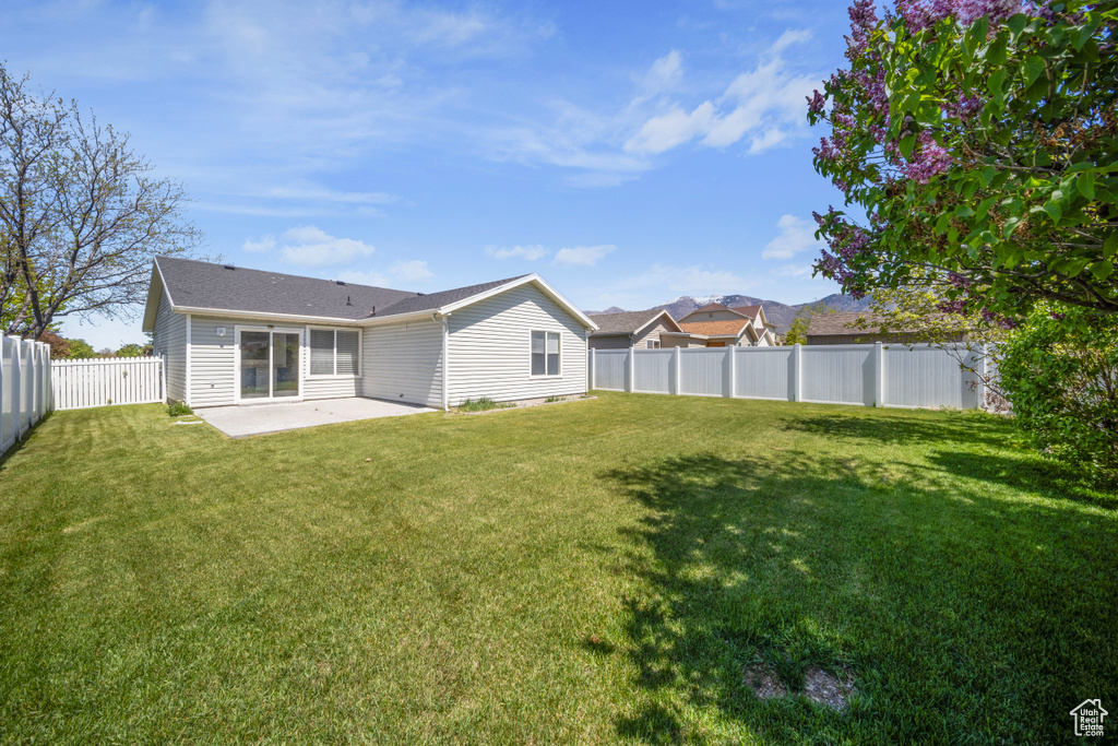 Rear view of property featuring a yard, a fenced backyard, and a patio area