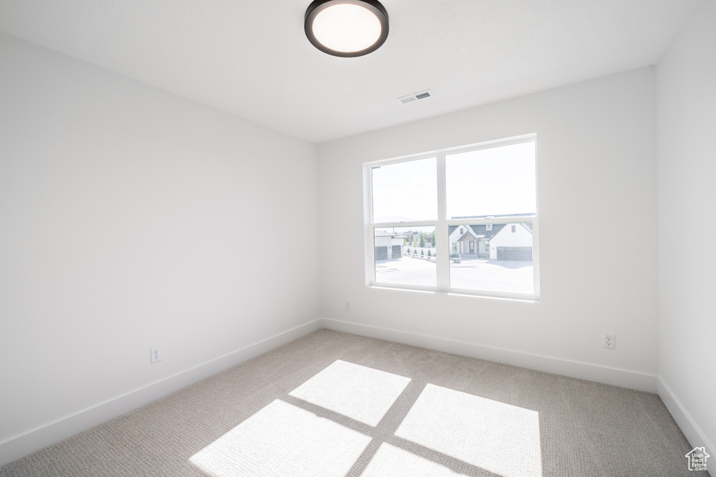 Empty room featuring light carpet and baseboards