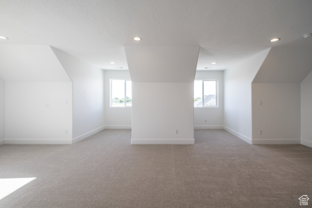 Bonus room with light colored carpet, recessed lighting, plenty of natural light, and a textured ceiling