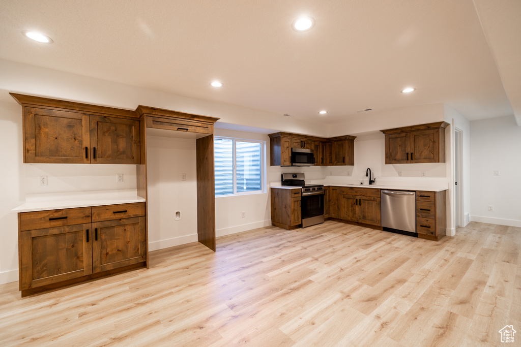 Kitchen featuring stainless steel appliances, recessed lighting, light wood-type flooring, and light countertops