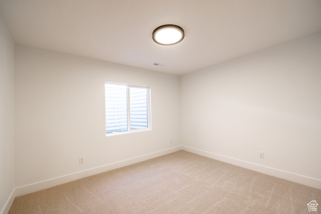 Empty room with light colored carpet and baseboards