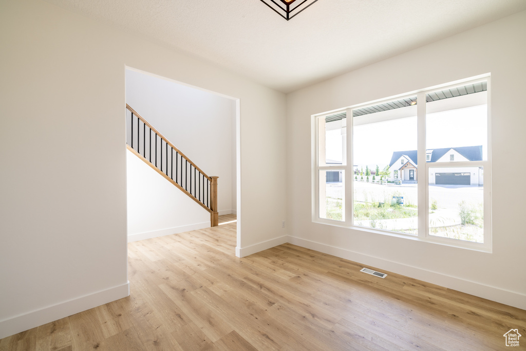 Unfurnished room with light wood finished floors and stairway